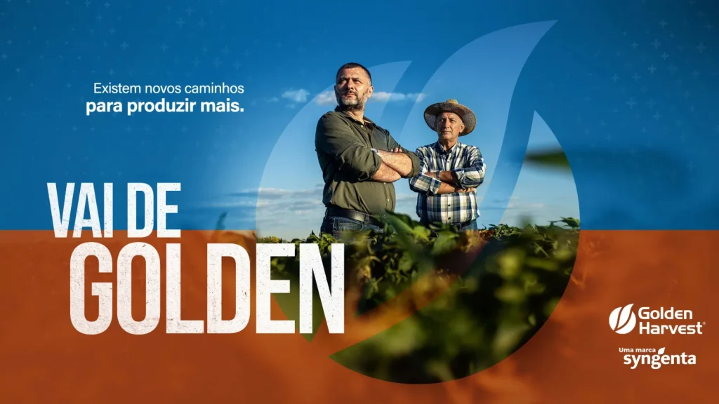 Banner publicitário horizontal com fundo dividido entre tons de azul e laranja, apresentando ao centro dois agricultores em pé em uma lavoura de soja sob céu limpo. Do lado esquerdo, destaca-se a frase "Existem novos caminhos para produzir mais." acima do texto em grandes letras brancas "VAI DE GOLDEN". No canto inferior direito, consta o logotipo da marca Golden Harvest com a assinatura "Uma marca Syngenta".